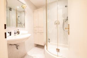 La salle de bains blanche est pourvue d'un lavabo et d'une douche. dans l'établissement Amici, à Garmisch-Partenkirchen