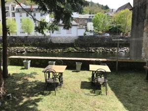 a couple of tables and chairs in front of a river at Appartement en coeur de ville 2 à 4 personnes in Bort-les-Orgues