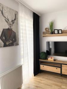 a living room with a television and a painting of a deer at Apartament Platinum Park in Stargard +13 photos