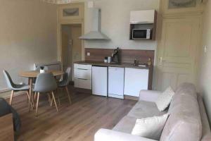 Una sala de estar con un sofá y una mesa y una cocina. en BeauneAppart - Centre- Climatisation - Parking gratuit, en Beaune
