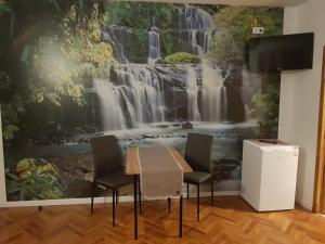 een tafel en stoelen voor een watervalmuurschildering bij CASA RAIA in Braşov