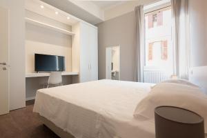 una camera da letto bianca con un letto e una TV di Good night Romeo - Eleganti Dimore a Verona