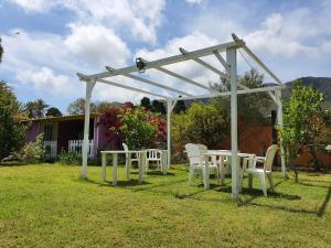 a white pergola with white tables and chairs in a yard at Sa Mariposa in Muravera