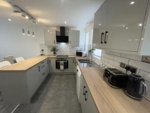 a kitchen with white cabinets and a wooden counter top at NEW Luxurious Modern Large 3 Bed House - Sleeps Up to 10 Guests - Sky Ultra HD, Sky Movies, Netflix, Disney Plus in Mansfield