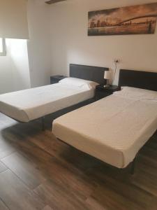 two beds in a room with wooden floors at Hotel Rural Quintanapalla in Quintanapalla