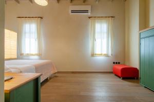 1 dormitorio con 1 cama y 1 silla roja en MyYellowHome en Ermoupoli