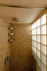 a bathroom with a shower and a brick wall at MyYellowHome in Ermoupoli