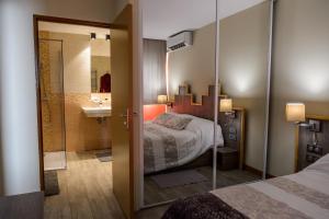 a bedroom with a bed and a bathroom with a sink at Hôtel Saint Roch in Martigues