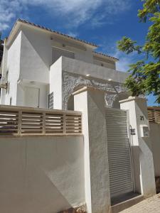 a white house with a gate and a fence at Casa MyA con terreno privado y parking compartido - a 800m de Playa Poniente in Benidorm