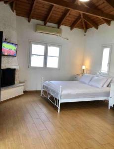 a bedroom with a white bed and a flat screen tv at Pool Guesthouse in Korinthos