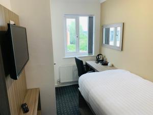 a hotel room with a bed and a desk and a television at De Regency Style Hotel in Redditch