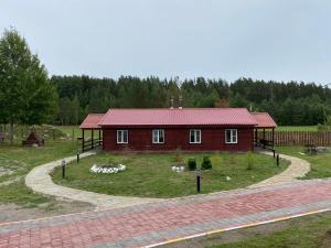 a small red house with a large yard in front of it at Эко-хутор "Ряйсяля-Райский Сад" in Mel'nikovo