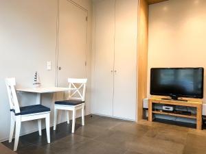 a living room with a television and a table with chairs at Studio KA06 Het Strandhuis in Vlissingen