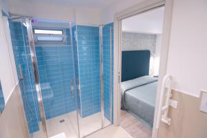 un piccolo bagno con doccia in vetro e un letto di HOTEL ADRIA BEACH a Rimini