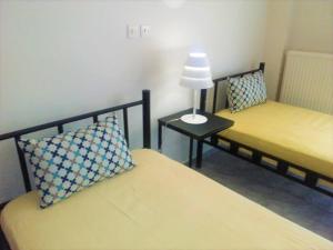 Habitación con 2 camas y una lámpara en una mesa. en Vacations in Patra Rooms en Patras