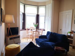 a living room with a blue couch and a table at Forth View Apartment in Stirling