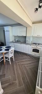 a large kitchen with white cabinets and a table at White rezidence in Curtea de Argeş