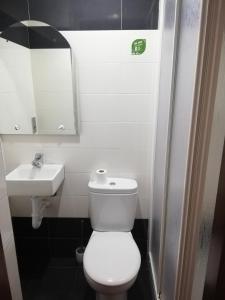 a bathroom with a white toilet and a sink at Albergue Buen Camino in Navarrete