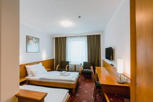 オロモウツにあるPrachárna Park Hotel Olomoucのベッド2台とデスクが備わるホテルルームです。