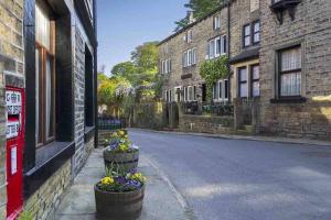 an empty street with flowers inpots on the side of buildings at Entire cottage in the beautiful Calder Valley in Halifax