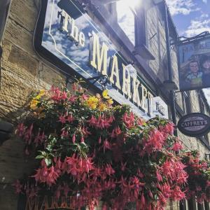 a sign for a market with flowers on the side of a building at Market in Elsecar