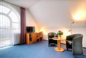 ミュンスターにあるHotel zur Prinzenbrückeの椅子2脚、テーブル、テレビが備わる客室です。