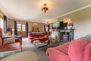 a living room with pink furniture and a tv at Fawlty Fields in Aynho