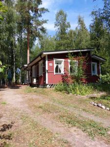 a red cabin in the middle of a dirt road at Ilmastoitu kesämökki Askolassa lähellä Porvoota in Askola