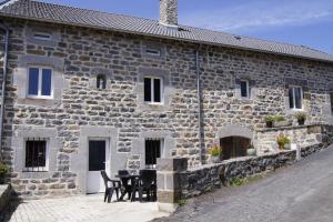 un edificio de piedra con una mesa y sillas delante de él en Chez Nave au pied du Meygal en Boussoulet