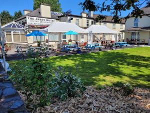 un patio con tavoli e ombrelloni di fronte a un edificio di Abbey Hotel a Ballyvourney Altre 23 foto