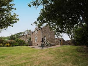 un gran edificio de ladrillo con un patio de césped en 1 Roddam Rigg Cottage, en Alnwick