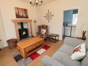 sala de estar con sofá y estufa de leña en 1 Roddam Rigg Cottage, en Alnwick