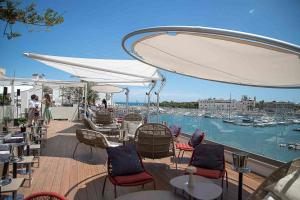 una terraza con mesas y sillas y vistas al puerto deportivo. en Ognissanti Restaurant Spa Hotel Rooftop, en Trani