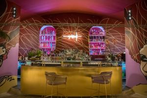 un bar con taburetes y paredes de color rosa y púrpura en Ognissanti Restaurant Spa Hotel Rooftop en Trani