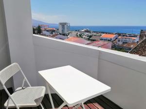 a white table and chair on a balcony with a view at Ladeira Loft - Sea View in the City Center in Ponta Delgada