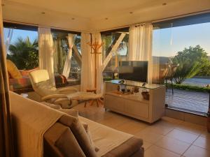 a living room with a television and large windows at Suite Independente Por do Sol Ferradura in Búzios