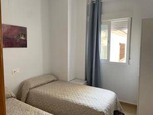 a small bedroom with two beds and a window at Apartamento Playa de la Guardia in Salobreña