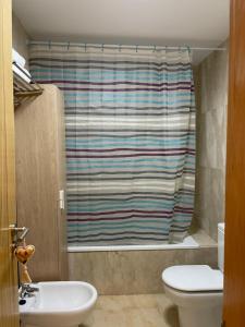 a bathroom with a toilet and a shower curtain at Apartamento Playa de la Guardia in Salobreña