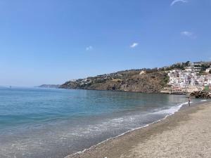 a beach with a person walking on the water at Apartamento Playa de la Guardia in Salobreña