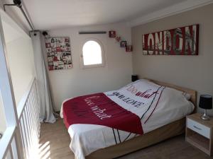 Schlafzimmer mit einem Bett mit einer roten und weißen Decke in der Unterkunft STUDIO PROCHE PARIS ET DISNEYLAND PARIS in Champigny-sur-Marne
