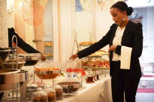 a woman standing in front of a buffet table holding a cake at Riad Palais Des Princesses & Spa in Marrakesh