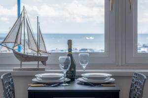 Ocean View - 1 Bedroom Apartment - Saundersfoot في ساندرزفوت: طاولة طعام مع زجاجة من النبيذ وكؤوس