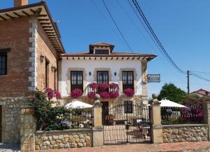 a building with flowers on the front of it at Posada La Cerra de San Roque in Santillana del Mar