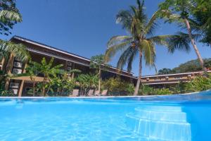 a swimming pool in front of a resort with palm trees at Cabo Velas Estates 30 in Matapalo