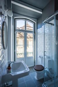 リスボンにあるホーム リスボン ホステルのバスルーム(洗面台、トイレ付)、窓が備わります。