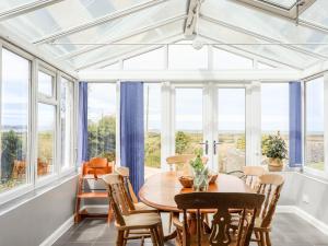 a dining room with a table and chairs and windows at Bodlasan Groes Cottage in Holyhead