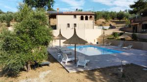 a pool with chairs and an umbrella and a house at Agriturismo I Cerroni Montescudaio in Montescudaio