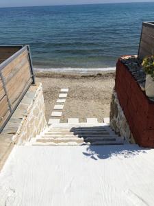 un escalier menant à la plage avec un banc dans l'établissement Venetico Beachfront Apartments & Suites - Sea View Studio, à Argassi