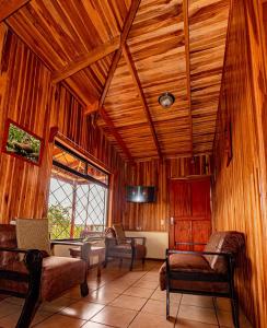 a living room with wooden ceilings and chairs and a tv at Cabañas La Pradera in Monteverde Costa Rica