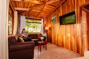 a woman sitting on a couch in a living room at Cabañas La Pradera in Monteverde Costa Rica